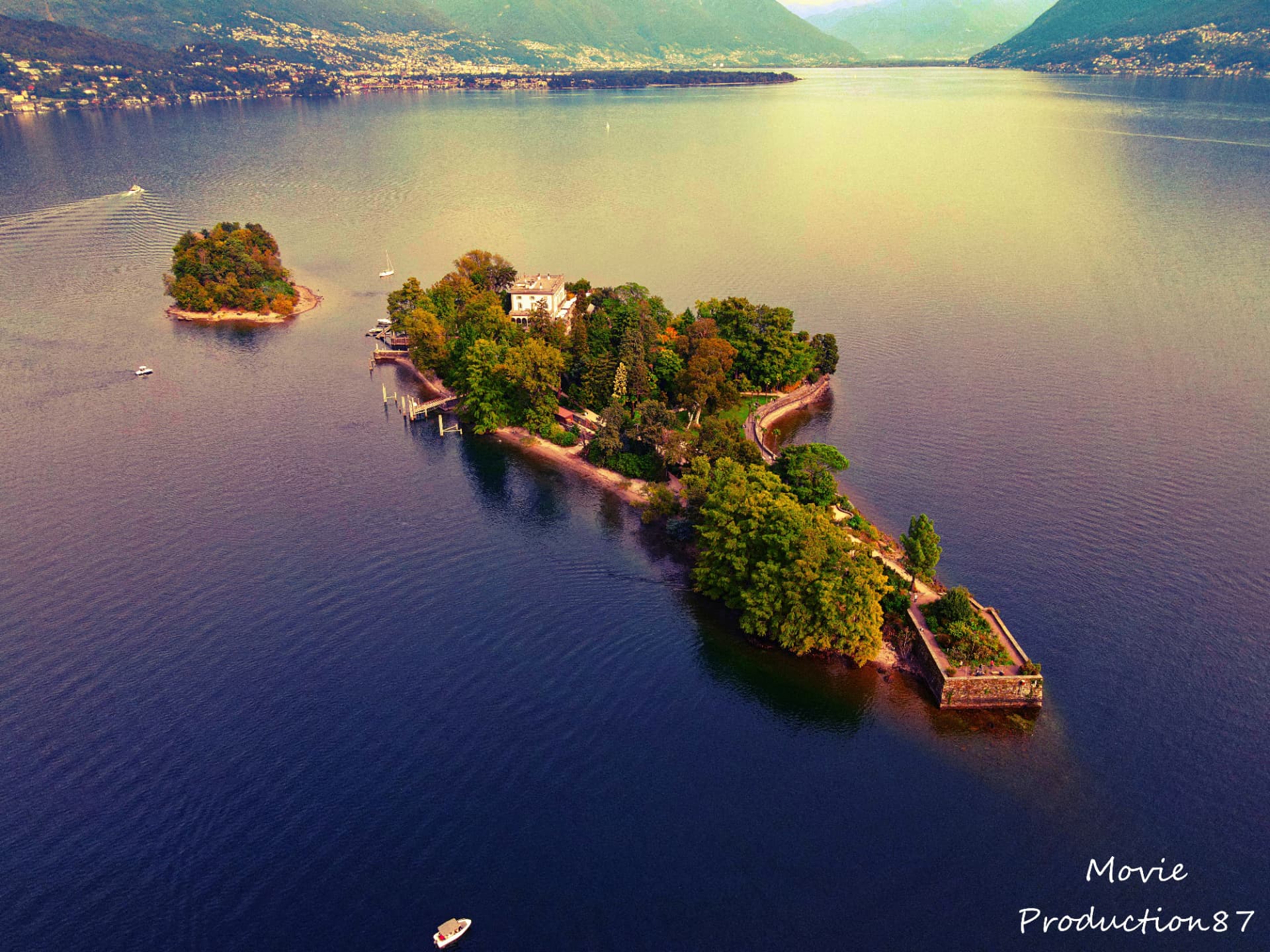 Drohnenaufnahme einer Insel im See mit Bergen im Hintergrund
